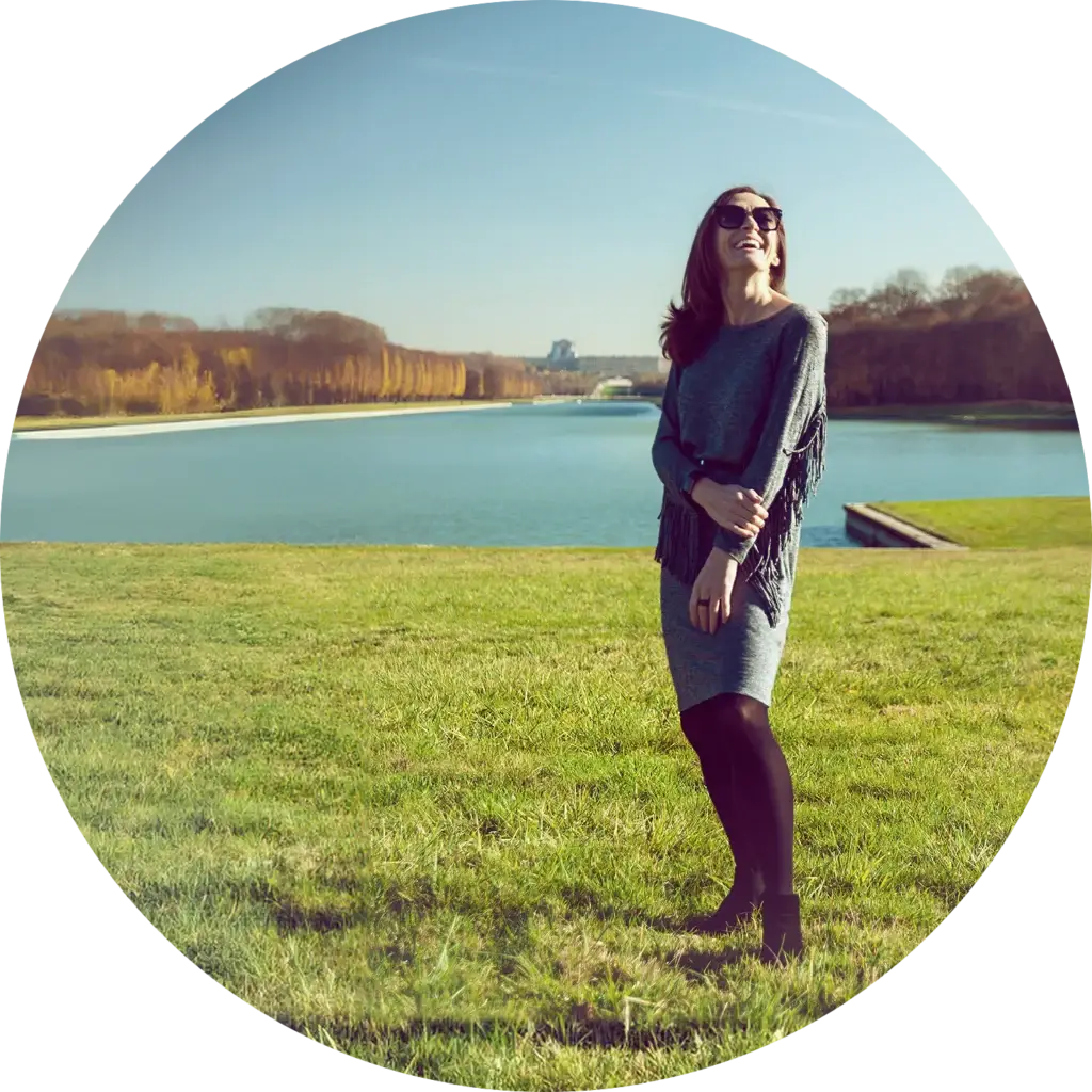 Slender, beautiful woman on the grassy grounds at the Palace Versailles in France as taken by artist MODERNAPERTURE, San Diego Professional Photographer.